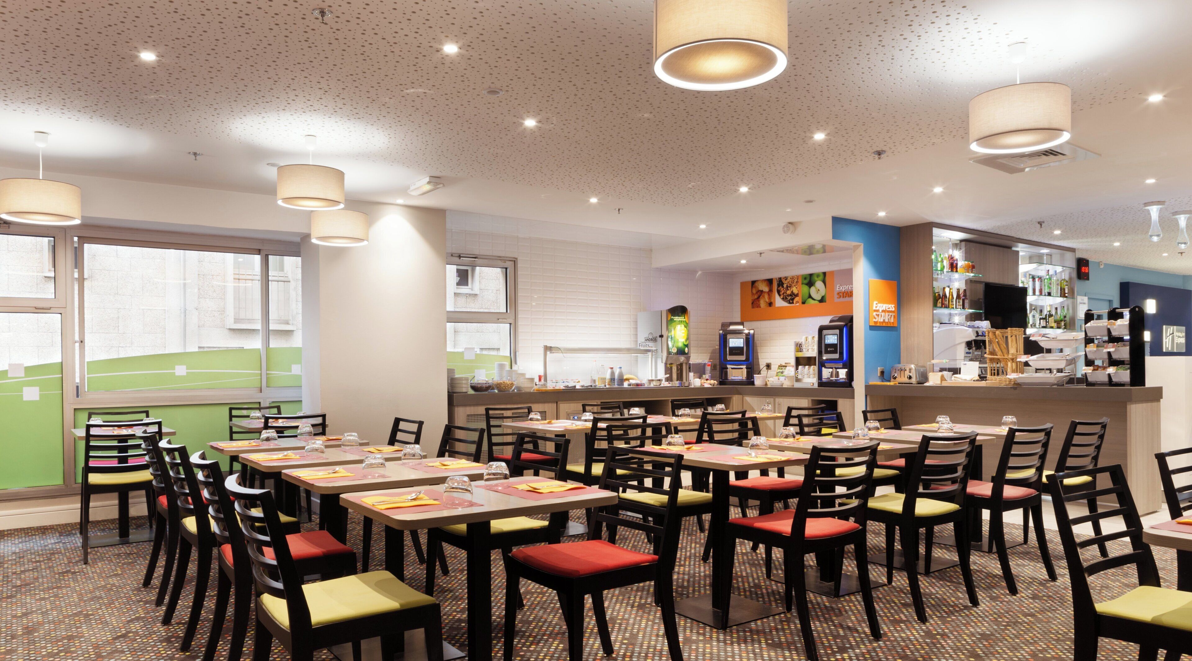Een restaurant met meerdere tafels en stoelen, een bar en een uitzicht op het buiten.