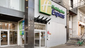 A Holiday Inn Express hotel entrance with a glass door, a bicycle parked outside, and a staircase to the right.