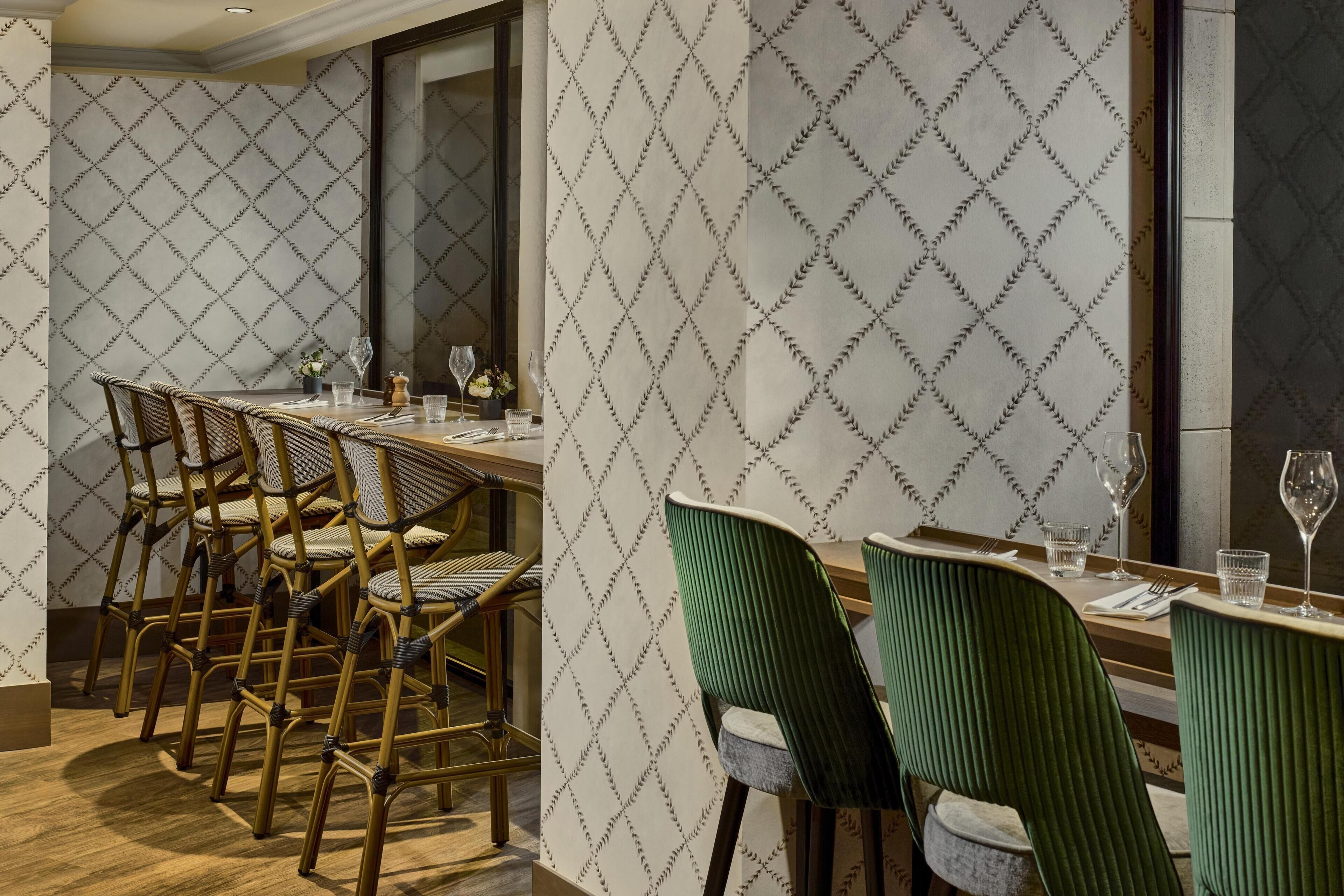 A dining area with a long table, multiple chairs, and a patterned wall.