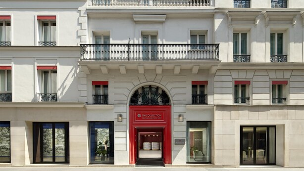 Un edificio de varios pisos con un llamativo letrero rojo que indica el NH Collection.