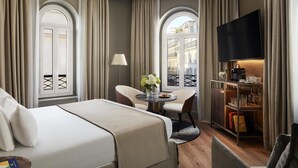 Una habitación de hotel con cama, escritorio, silla, televisor y estantería.