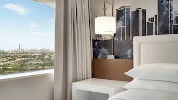 Une chambre d’hôtel avec vue sur la ville, un lit blanc, une table de chevet et une lampe fixée au mur.