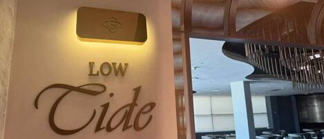 A sign with 'LOW Tide' and a modern interior with seating and a ceiling design.