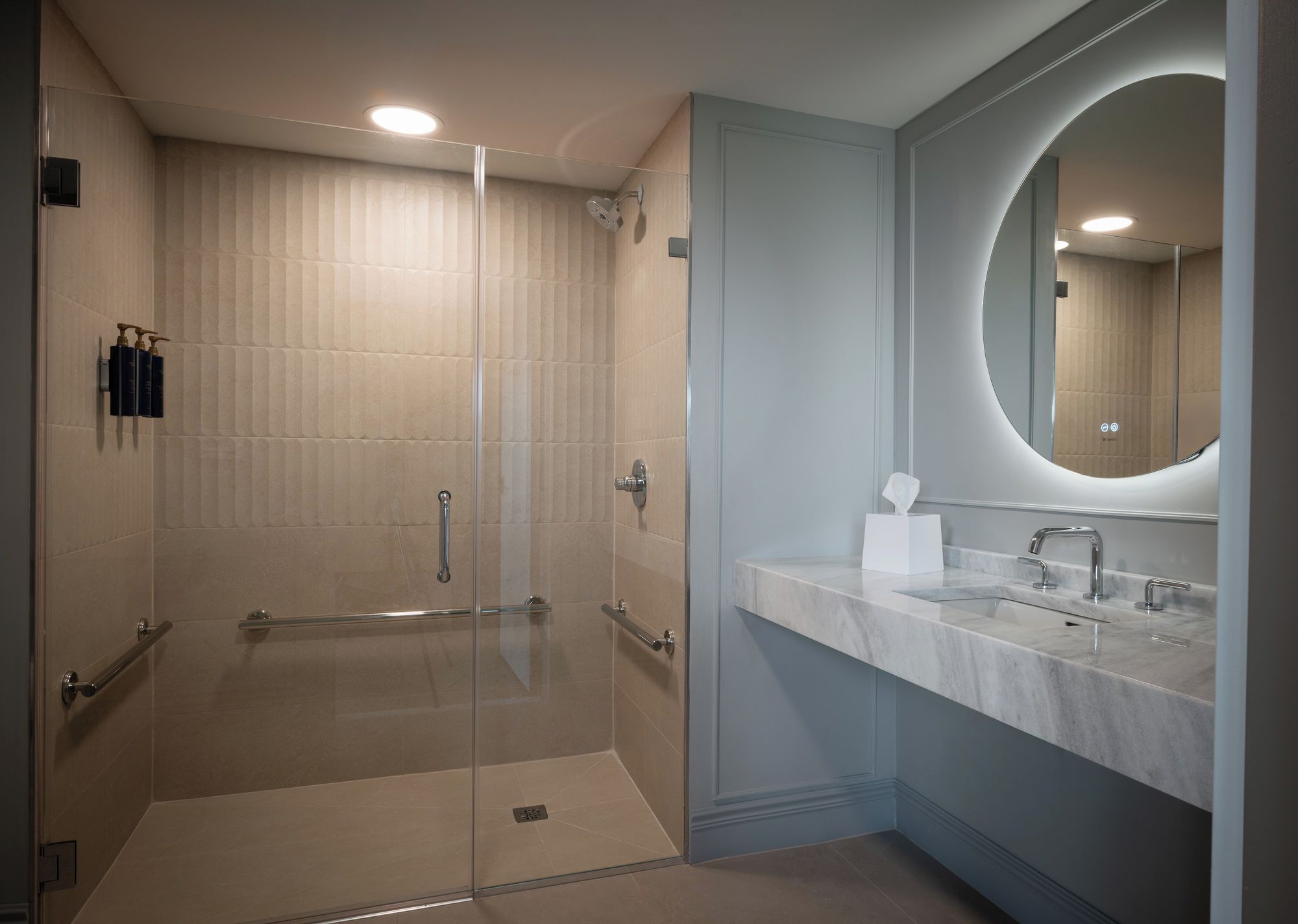 A modern bathroom with a glass shower enclosure, a marble sink, and a large mirror.