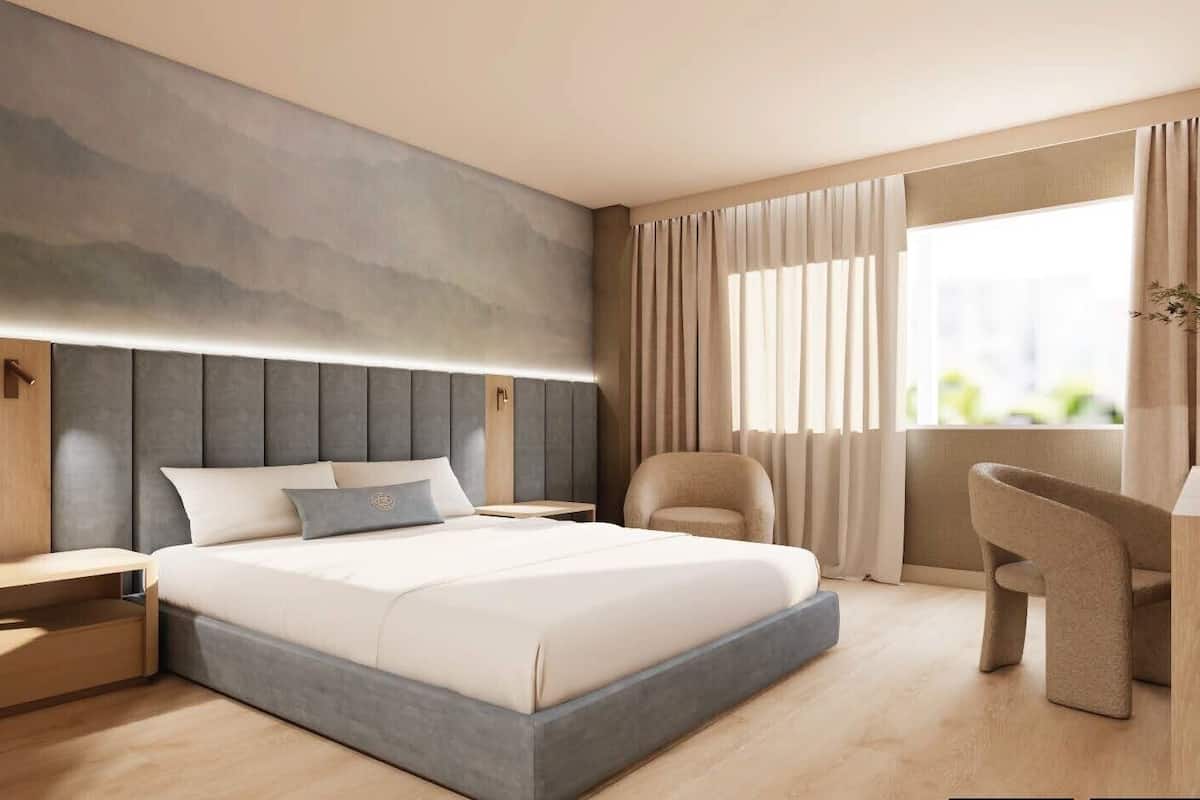 Ein modernes Hotelzimmer mit einem großen Bett, einem Schreibtisch und einem Sessel.