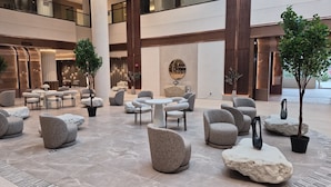 A spacious lobby with modern seating, a central round table, and a large mirror on the wall. - World of Blue (East Rutherford)