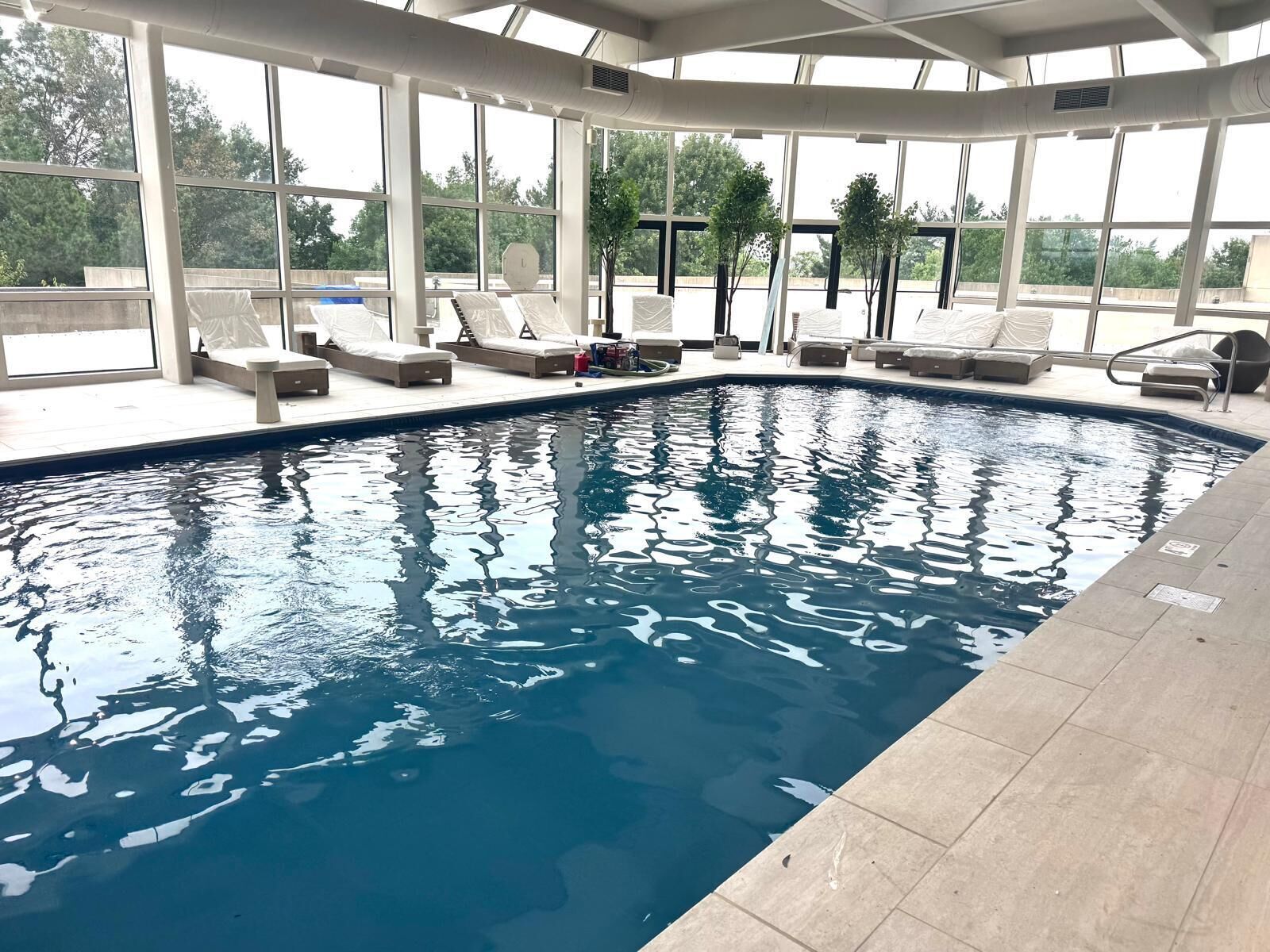 Une piscine intérieure à l’eau d’un bleu cristallin, entourée de chaises longues et d’un espace salon abrité.