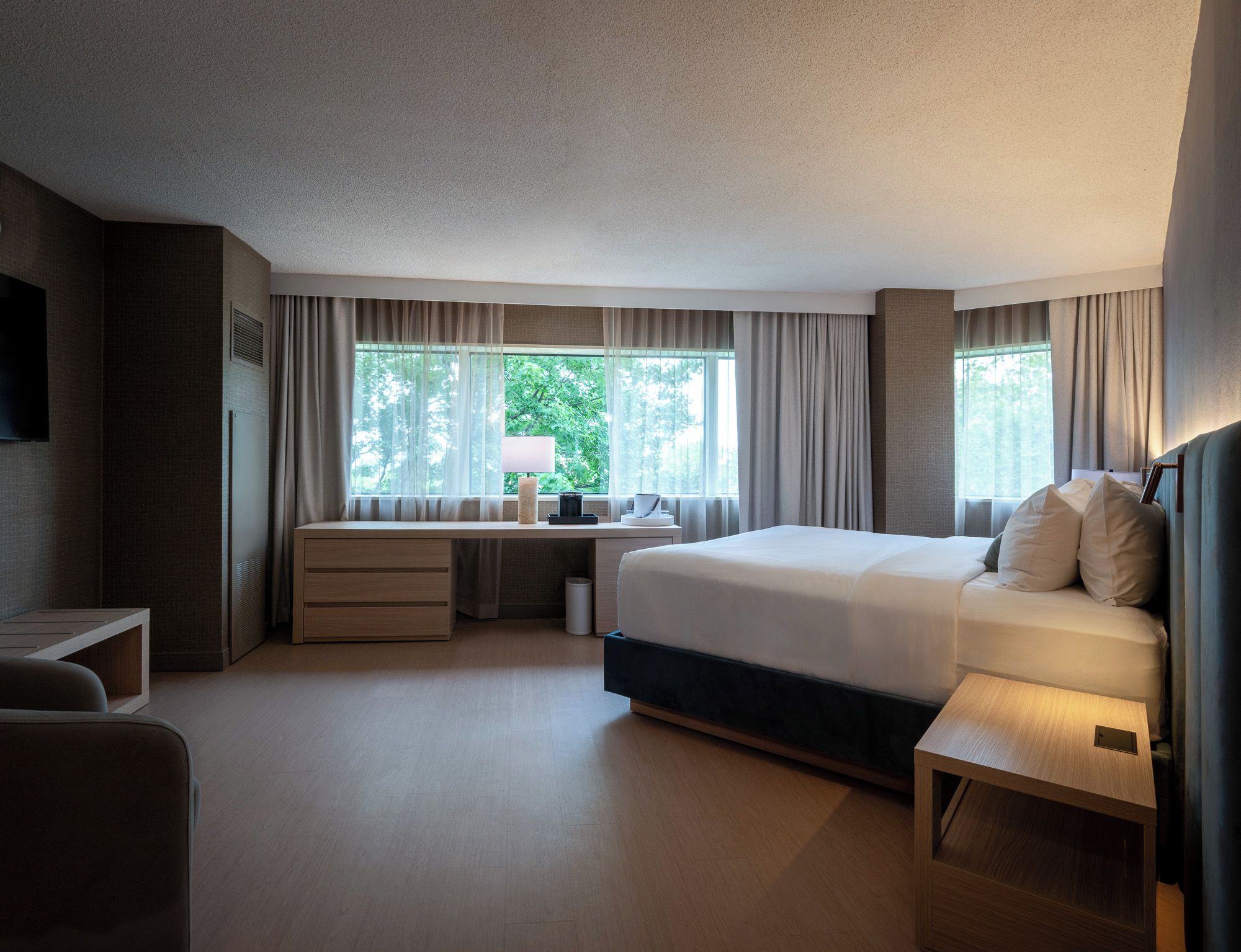 A modern hotel room with a large bed, a desk, and a TV.
