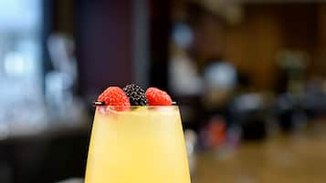 A cocktail glass with a fruit garnish on a wooden bar counter.