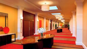 Ein Hotelgang mit rotem Teppich, Holzbude und einem großen Spiegel.