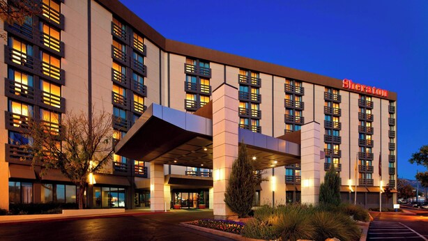 Ein Sheraton Hotel mit moderner Fassade, mehreren Balkonen und einem gut beleuchteten Eingang.