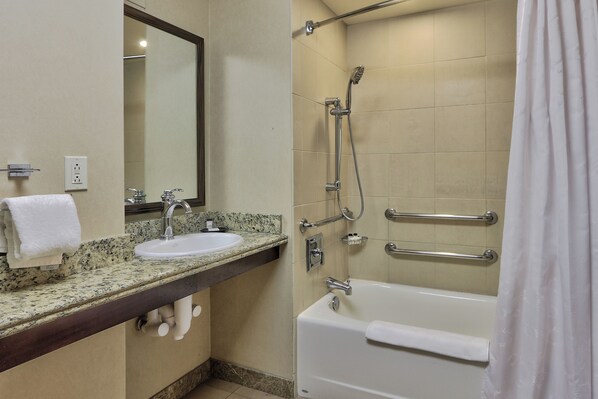 A bathroom with a sink, mirror, and bathtub.
