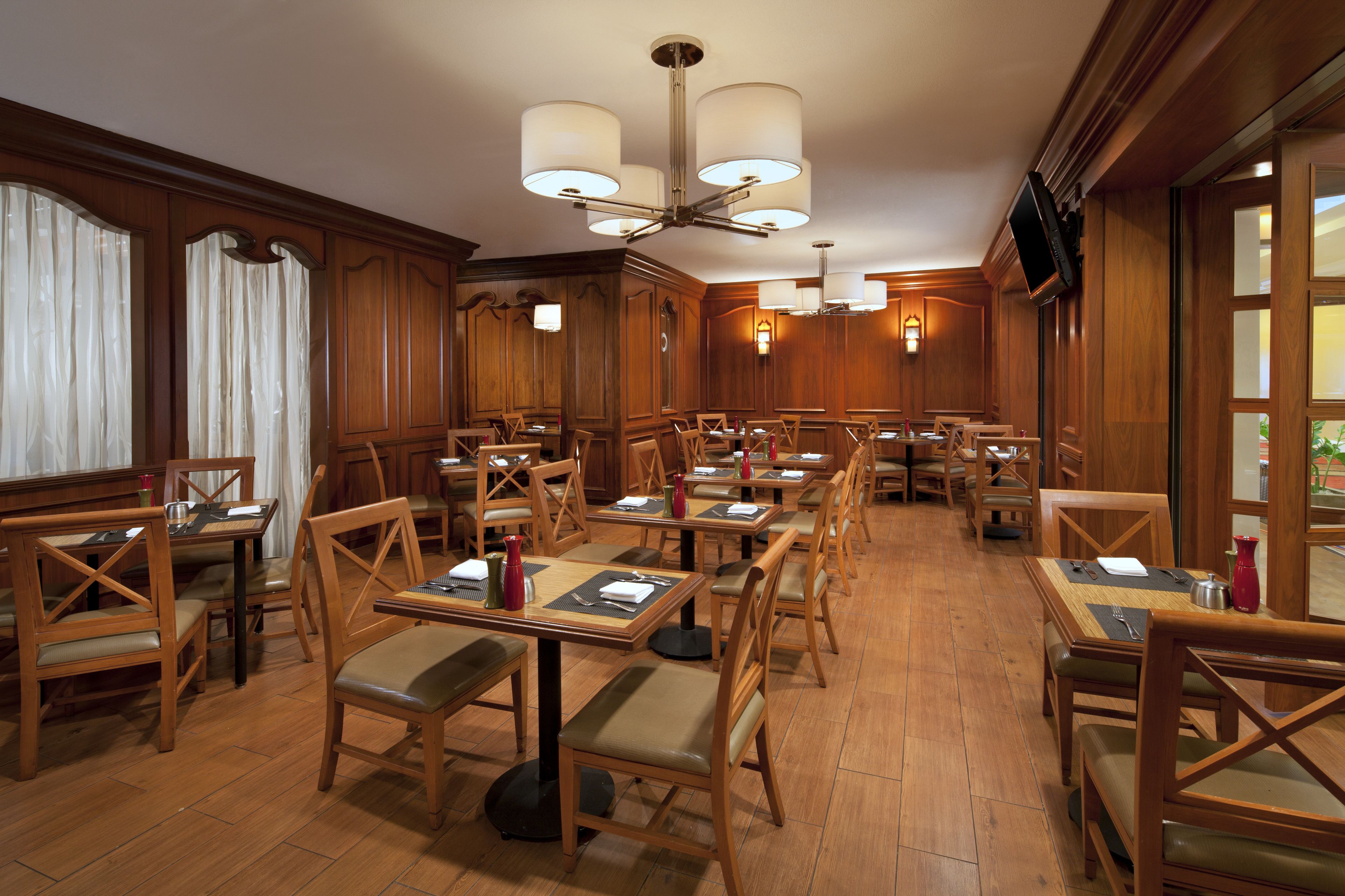 A restaurant with wooden furniture, multiple tables, and a chandelier.