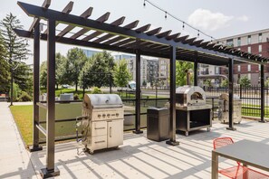 Eine Außenpatio mit Pergola, zwei Grillanlagen und einer Sitzgelegenheit.