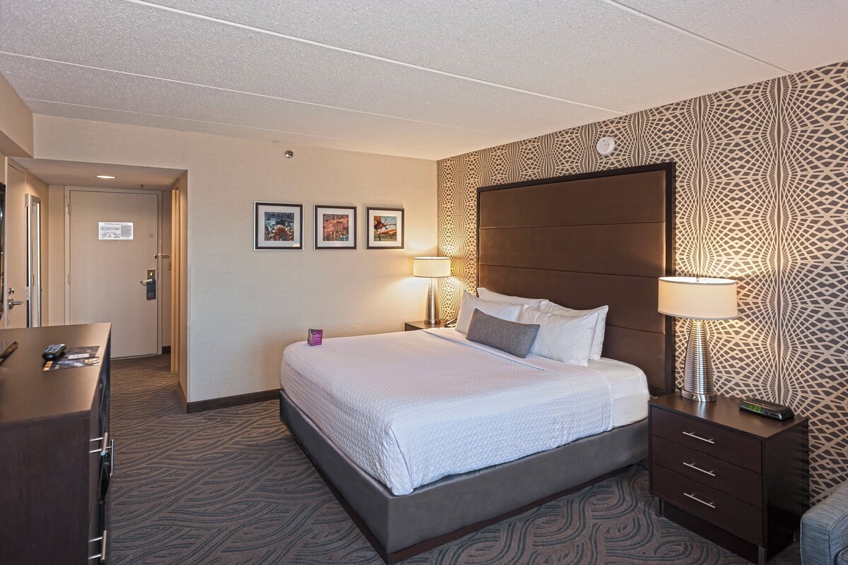 Ein Hotelzimmer mit einem großen Bett, Nachttischlampen, einem Schminktisch und einer Wand mit Muster.