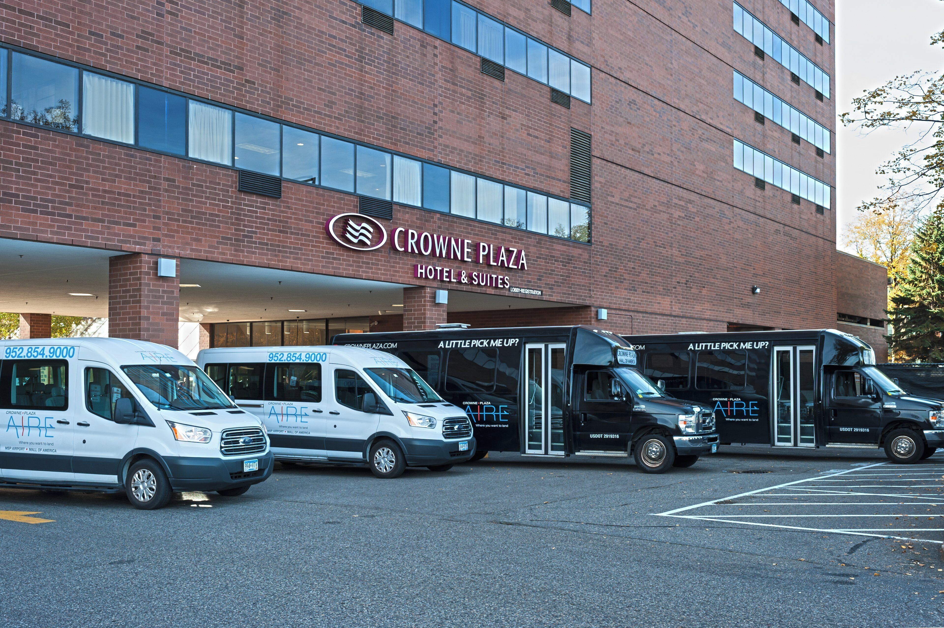 A hotel with a brick facade, multiple entry points, and a parking lot with service vehicles.
