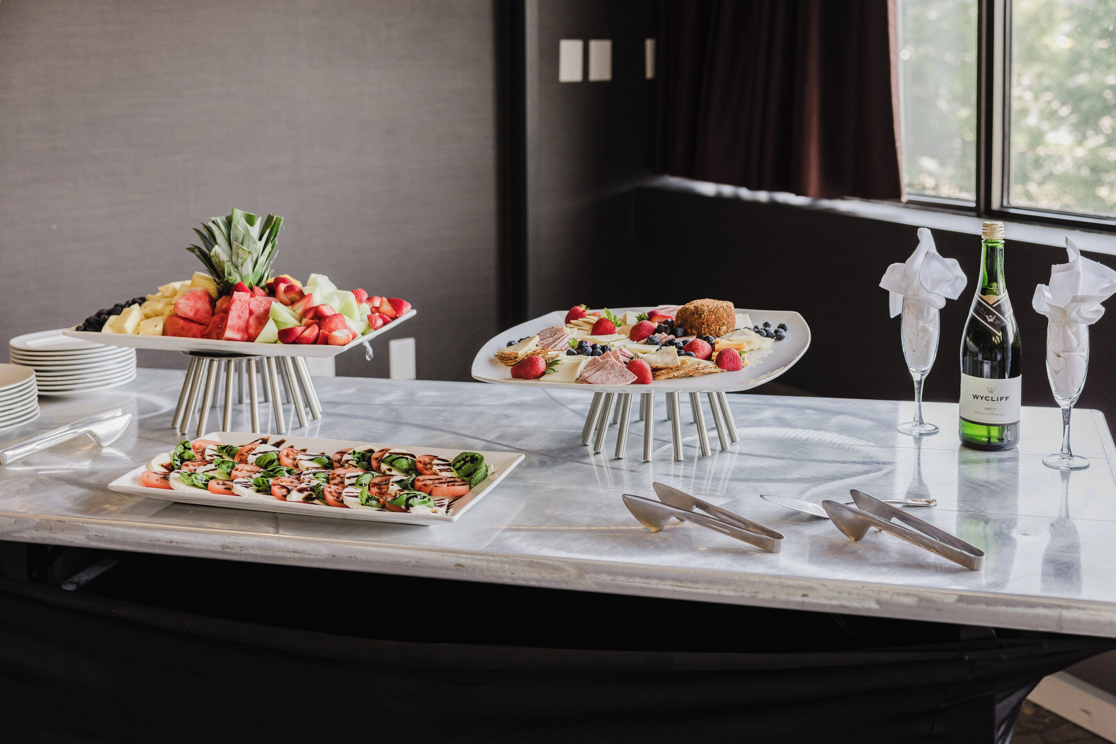 A buffet table with various food items and wine glasses.