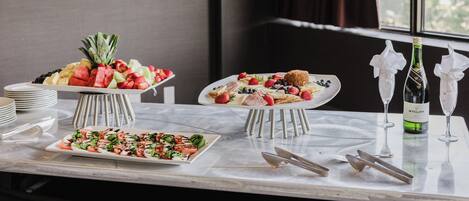 A buffet table with various food items and wine glasses.
