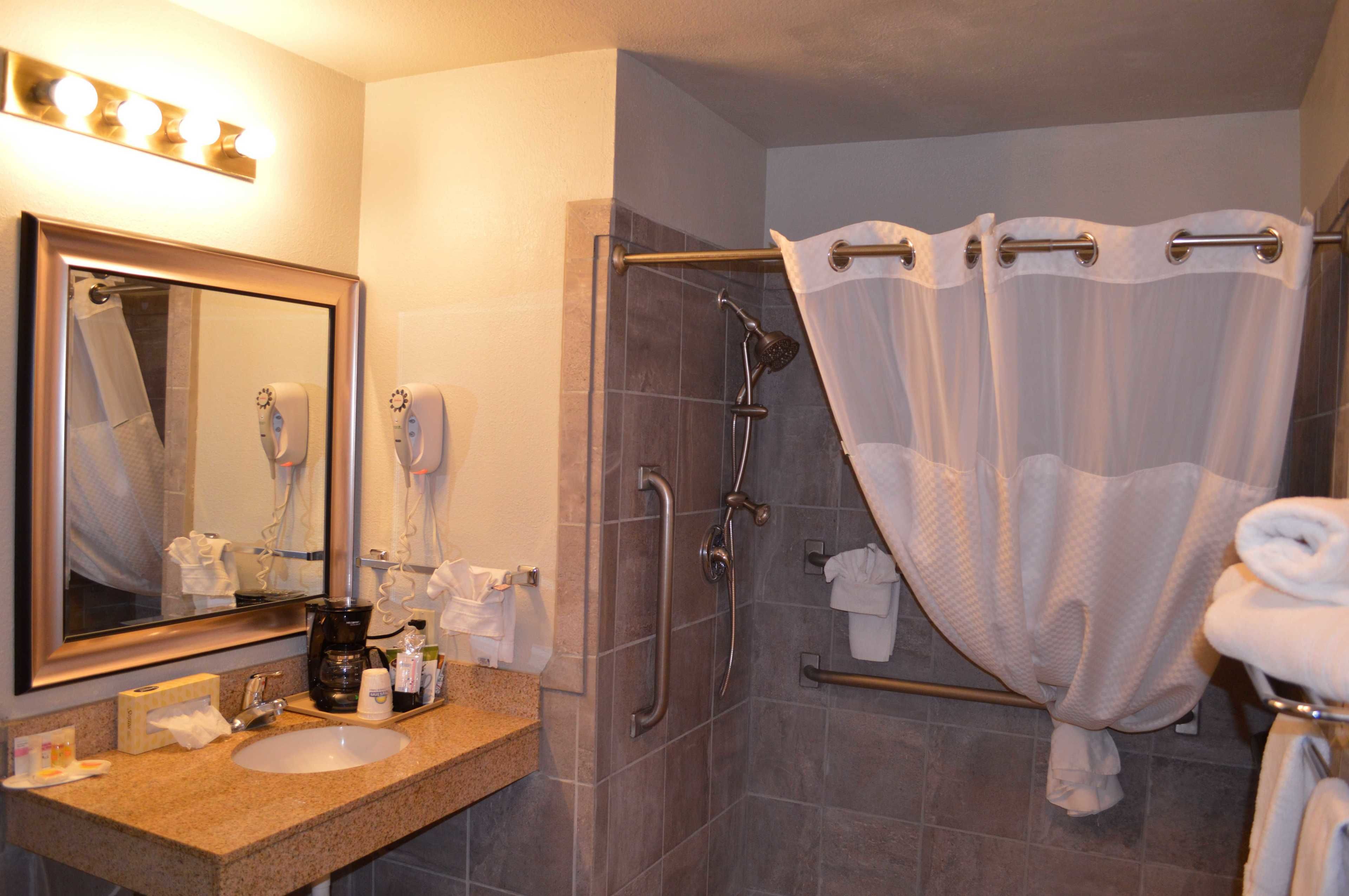 A bathroom with a sink, mirror, shower with a glass door, and a towel rack.