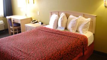 A hotel room with a bed, a desk, a chair, and a nightstand.