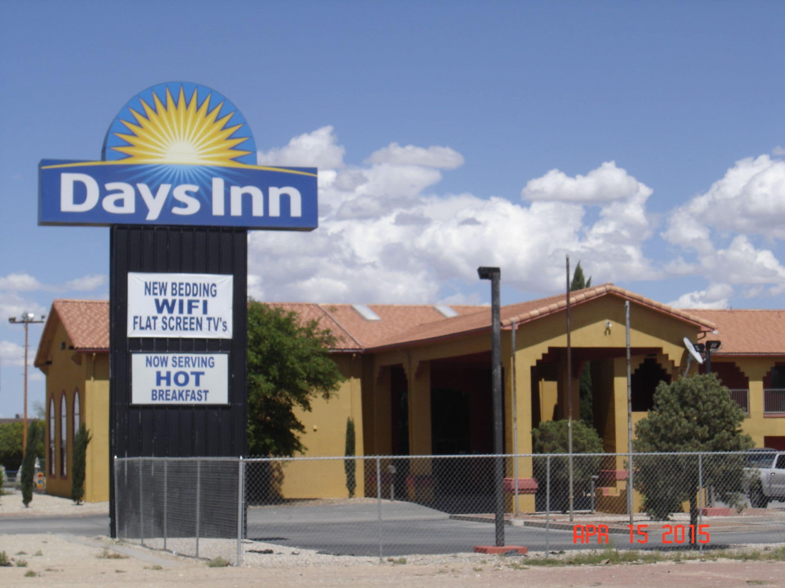 A Days Inn sign with amenities including new bedding, WiFi, flat-screen TVs, and a breakfast restaurant.