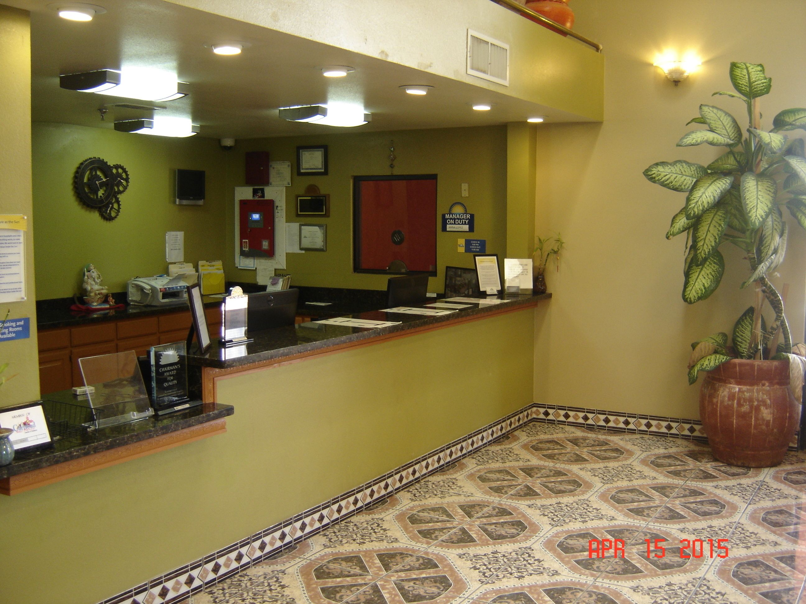 A reception area with a counter, a fire extinguisher, a door, and a potted plant.