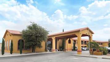Hotel entrance with a covered area featuring arches and a red-tiled roof.