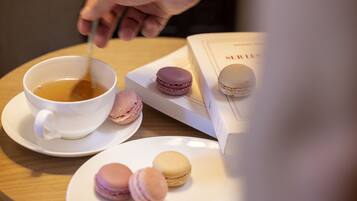 Una tazza di tè, un libro e dei macarons su un tavolo.