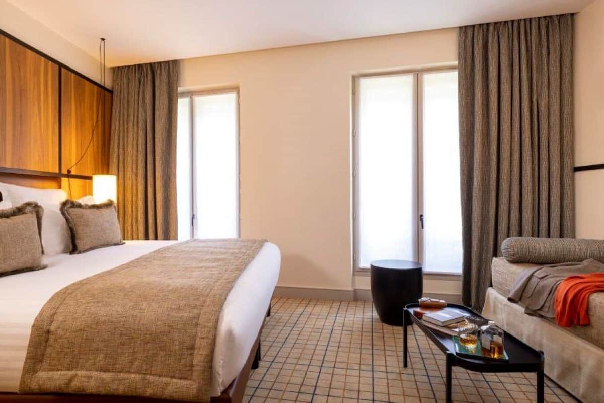 Ett hotellrum med en stor säng, en soffa, ett litet bord och ett fönster.