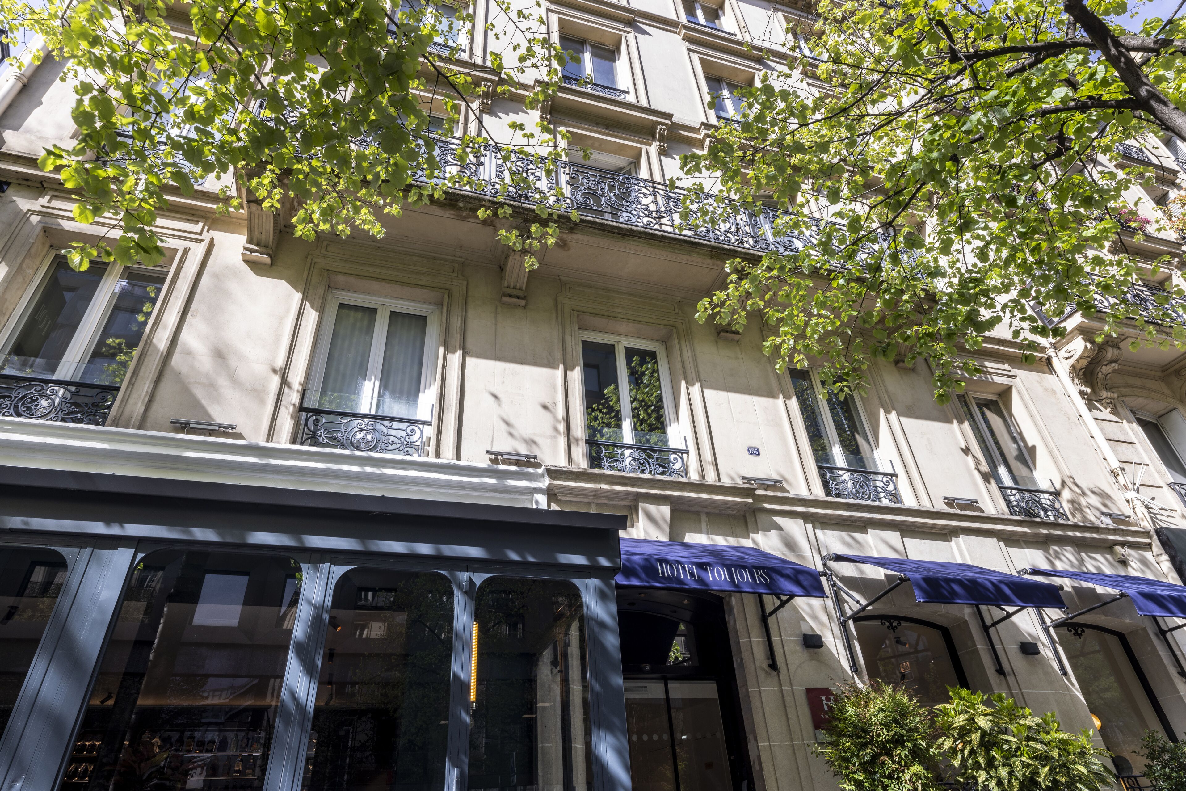 Ein mehrstöckiges Gebäude mit Balkonen, großen Fenstern und einem blauen Vordach mit der Aufschrift 'HOTEL TOURS'.