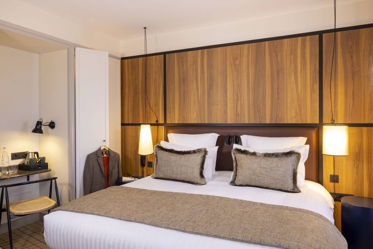 Ett hotellrum med en stor säng, två sänglampor, ett skrivbord med en lampa och en stol.