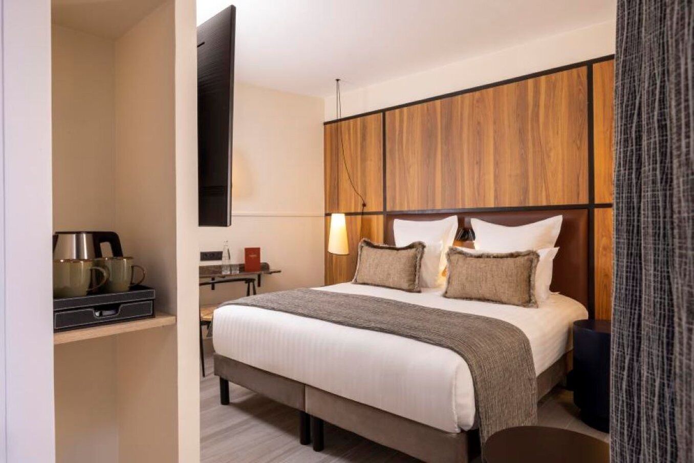 Une chambre d’hôtel équipée d’un lit, d’une table de chevet, d’une lampe et d’un téléviseur fixé au mur.