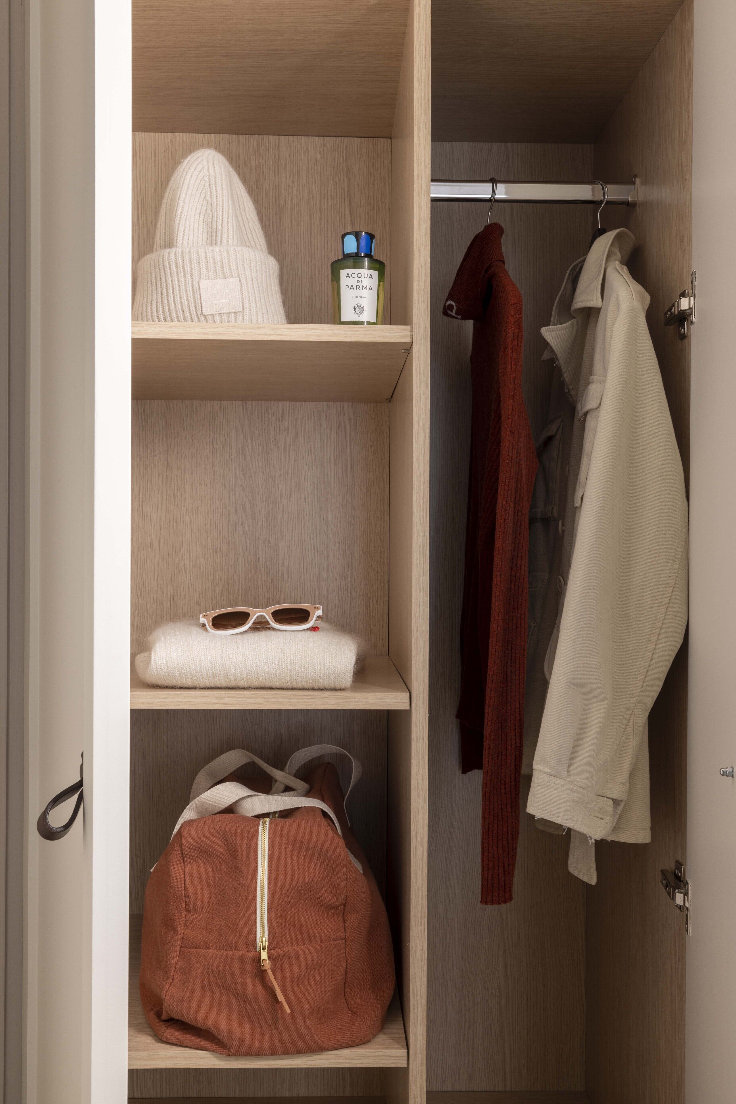 Un placard avec des étagères contenant un bonnet blanc, une paire de lunettes de soleil et un sac marron.
