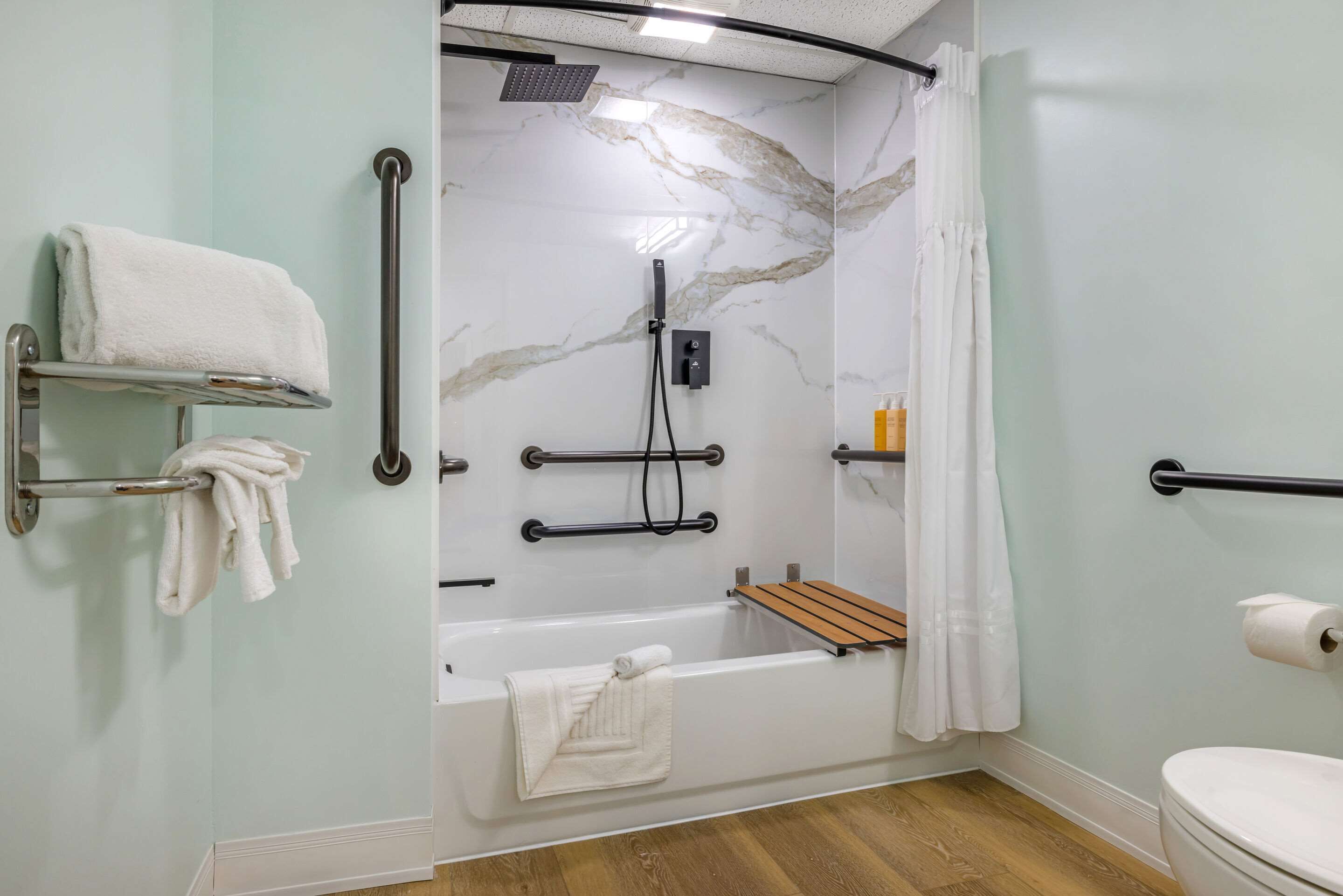 A bathroom with a shower, toilet, and two towel racks.