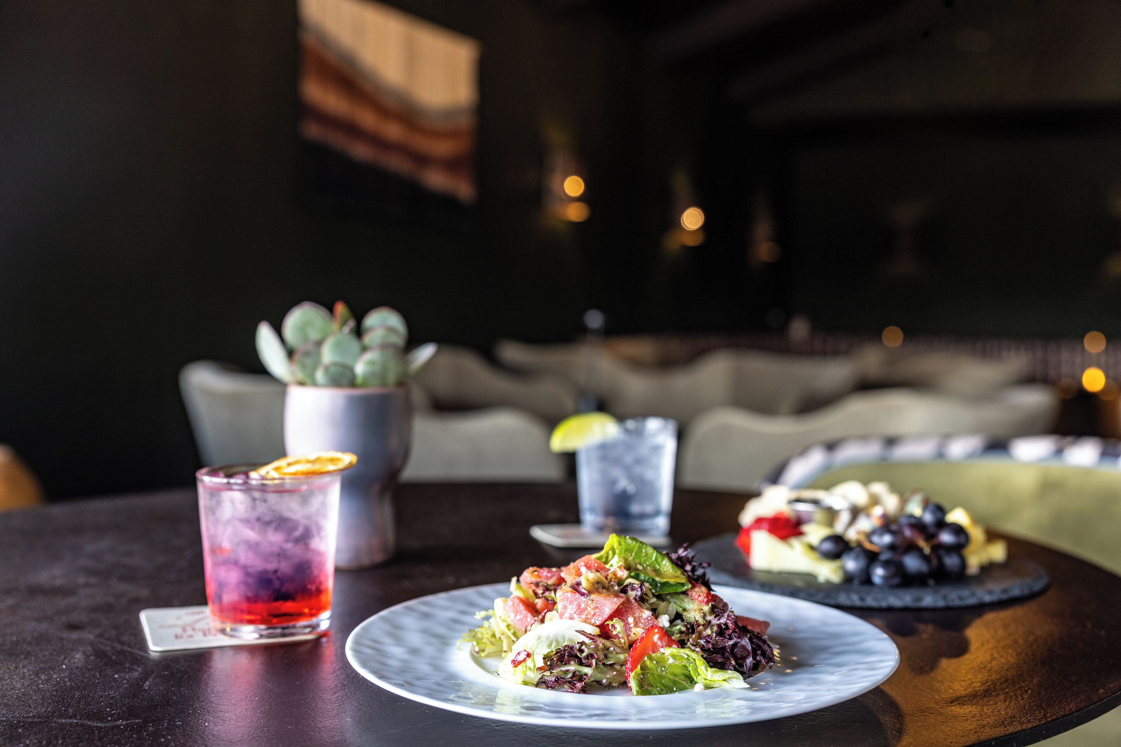 A dining table with a salad, a drink, and a dessert plate.