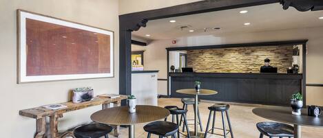 A modern interior with a bar area, seating, and a large abstract painting.