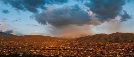 Vista panorámica de una ciudad con montañas al fondo y un cielo nublado.