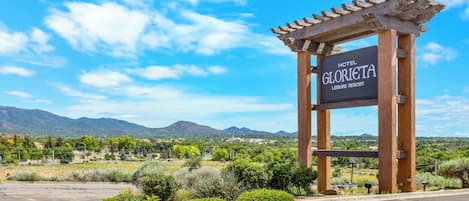 Señal del Hotel Gloria Vista Resort, con vistas a montañas y vegetación al fondo.