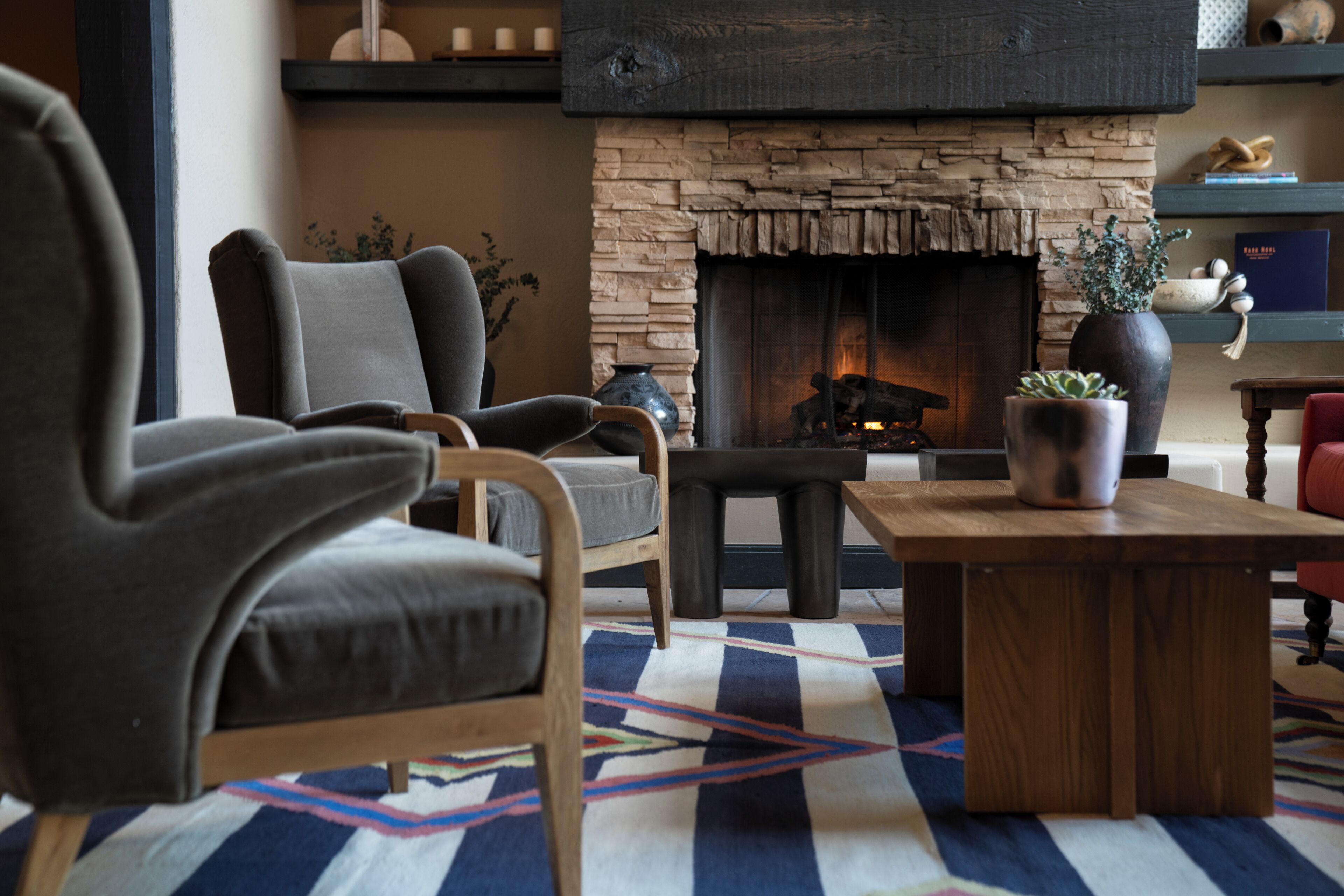 A cozy living room with a stone fireplace, comfortable seating, and a decorative rug.