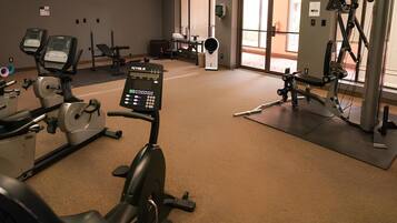Un gimnasio con máquinas de cardio, equipo de levantamiento de pesas y un panel de control.