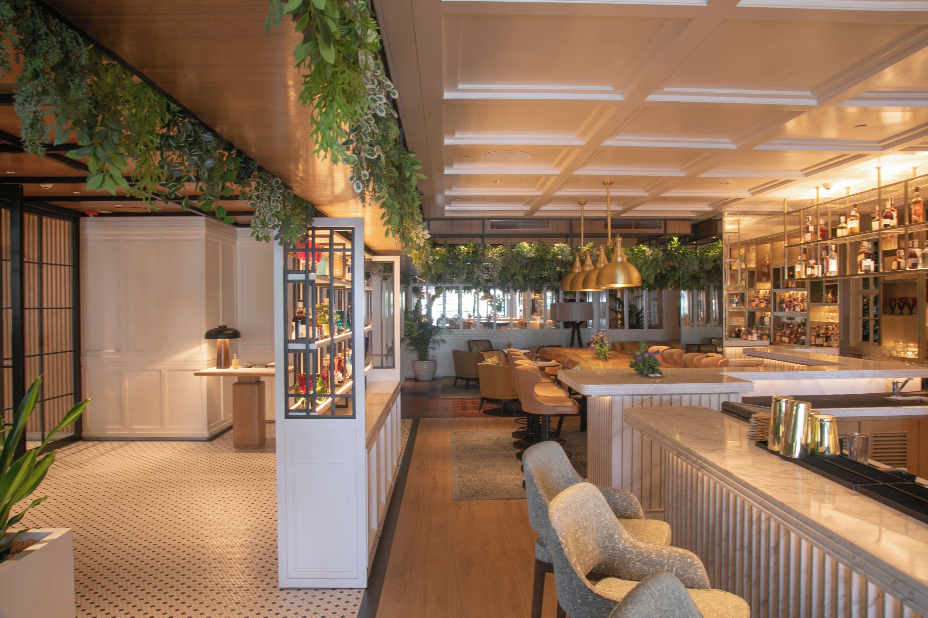 A modern bar area with seating, a bar counter, and a display of bottles.