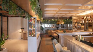 A modern bar area with seating, a bar counter, and a display of bottles.
