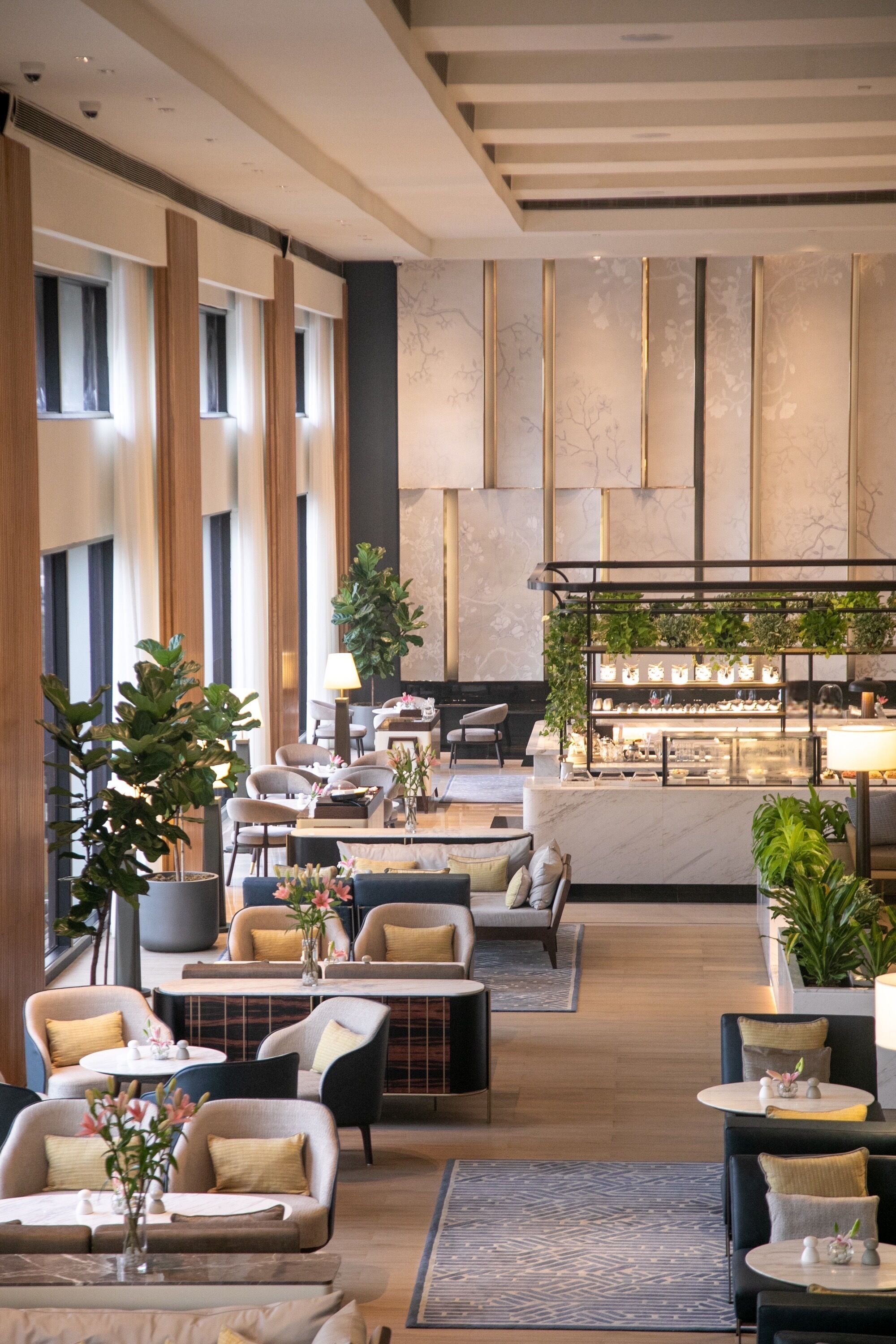 A modern hotel lobby with seating areas, a bar, and a reception desk.