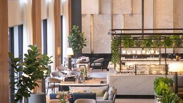 A modern hotel lobby with seating areas, a bar, and a reception desk.