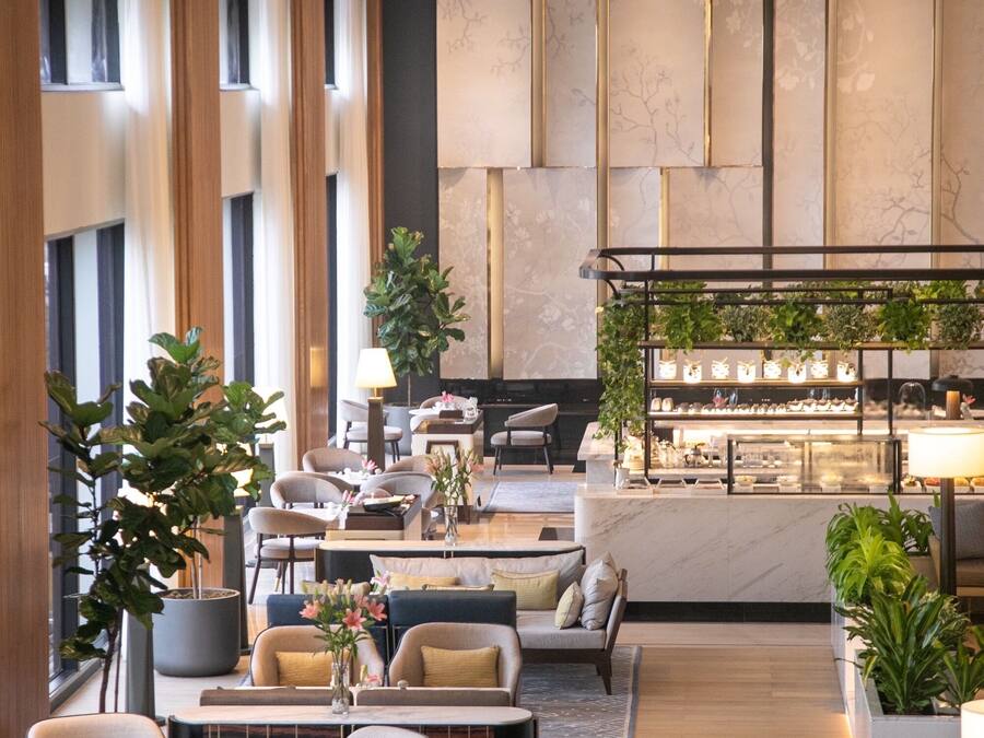 A modern hotel lobby with seating areas, a bar, and a reception desk.