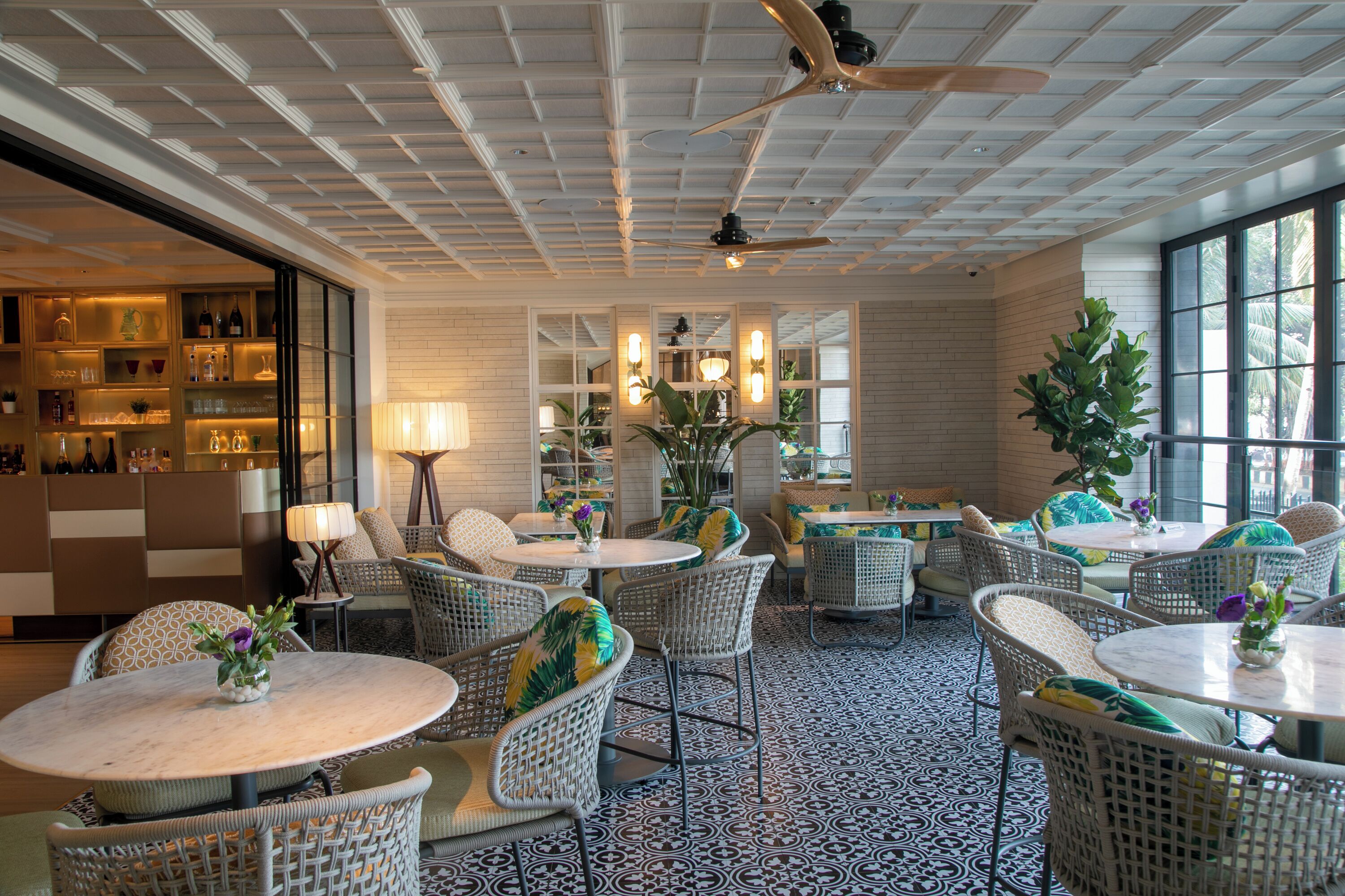 A hotel lobby with wicker furniture, a ceiling fan, and a patterned floor.