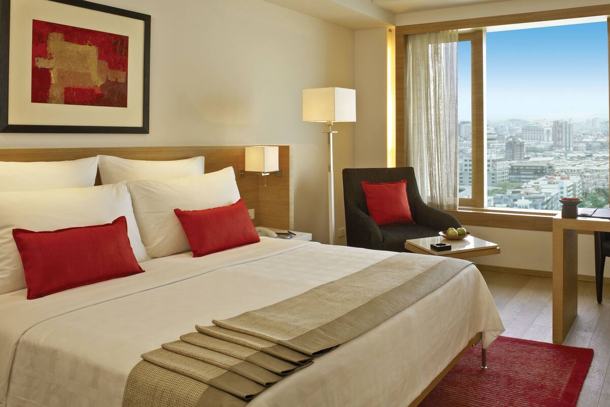Une chambre d’hôtel avec un grand lit, une chaise, un bureau et une vue sur la ville.