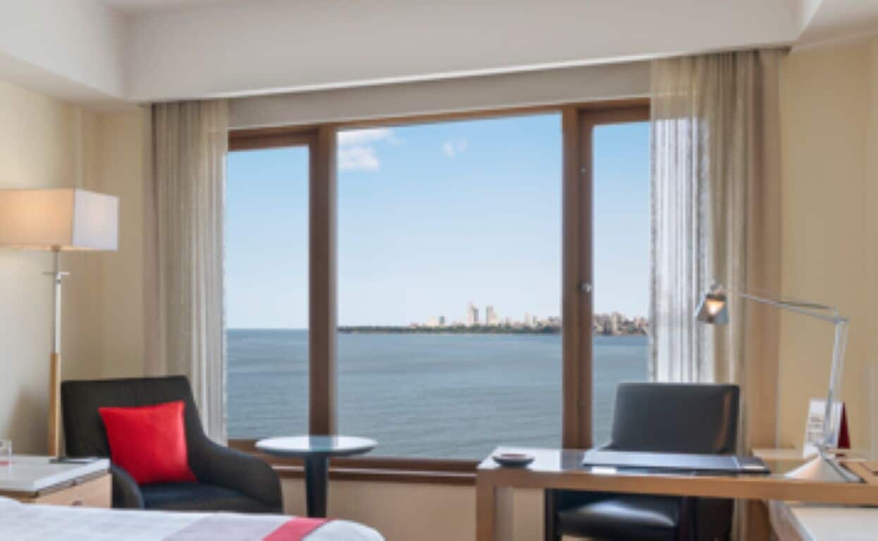 Una habitación de hotel con un ventanal grande, un escritorio con una computadora portátil, una silla y una cama.