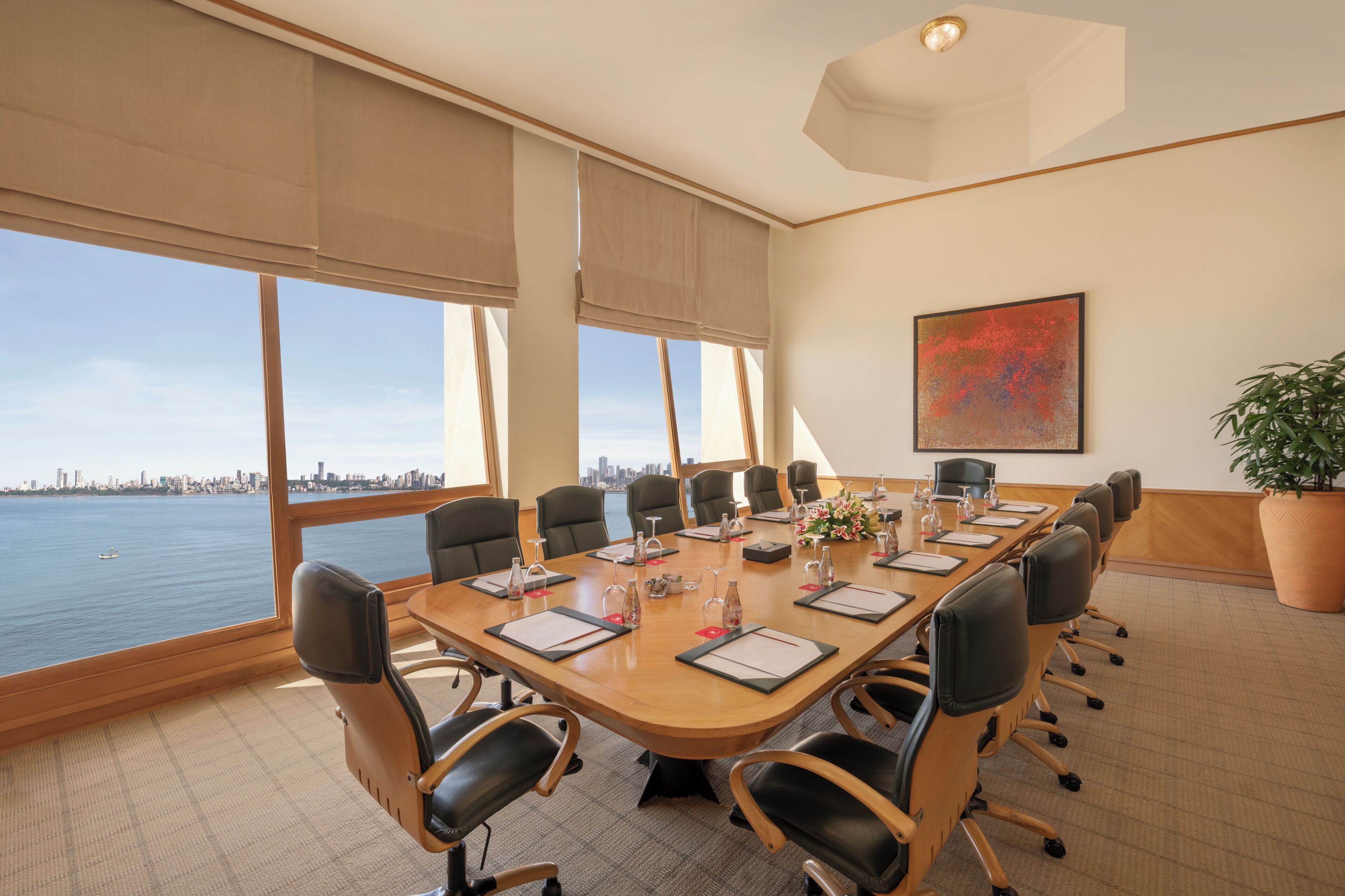 Un salón de conferencias con una gran mesa, sillas y vistas a la ciudad.