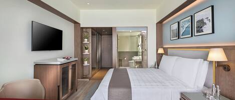 Una habitación de hotel con cama, escritorio, televisión, baño y zona de comedor.